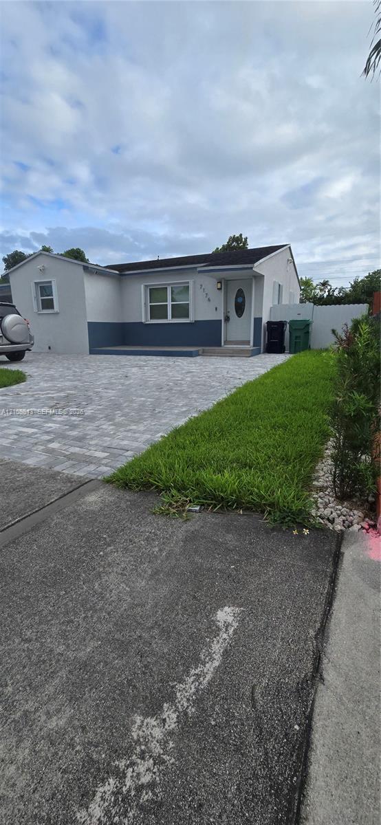 Single-story exterior featuring a two-tone smooth stucco finish, paver driveway, front porch, and horizontal sliding windows