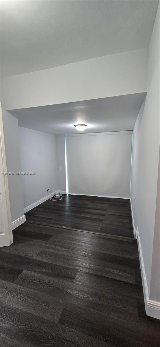 Interior space featuring dark wood-finish flooring, recessed architectural soffit, and flush-mount ceiling lighting
