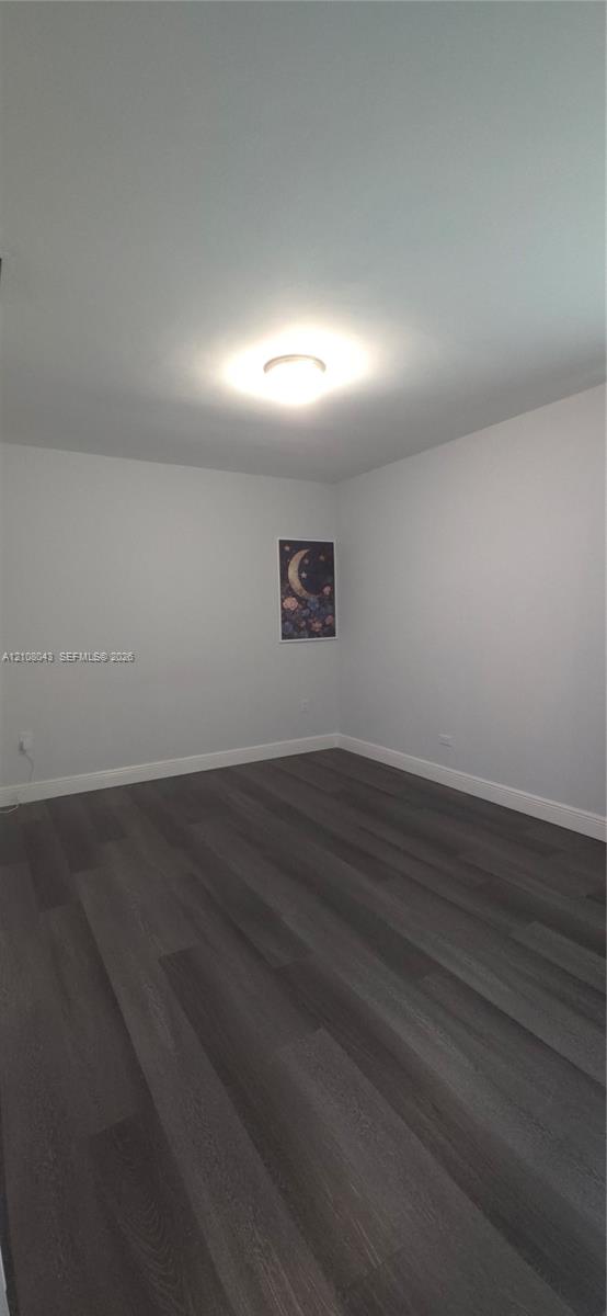 Room featuring neutral wall paint, dark wood-finish flooring, and a flush-mount ceiling fixture