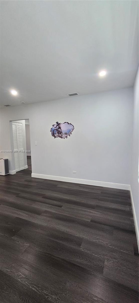 Interior space featuring dark wood-finish flooring, recessed ceiling lighting, and a bi-fold door