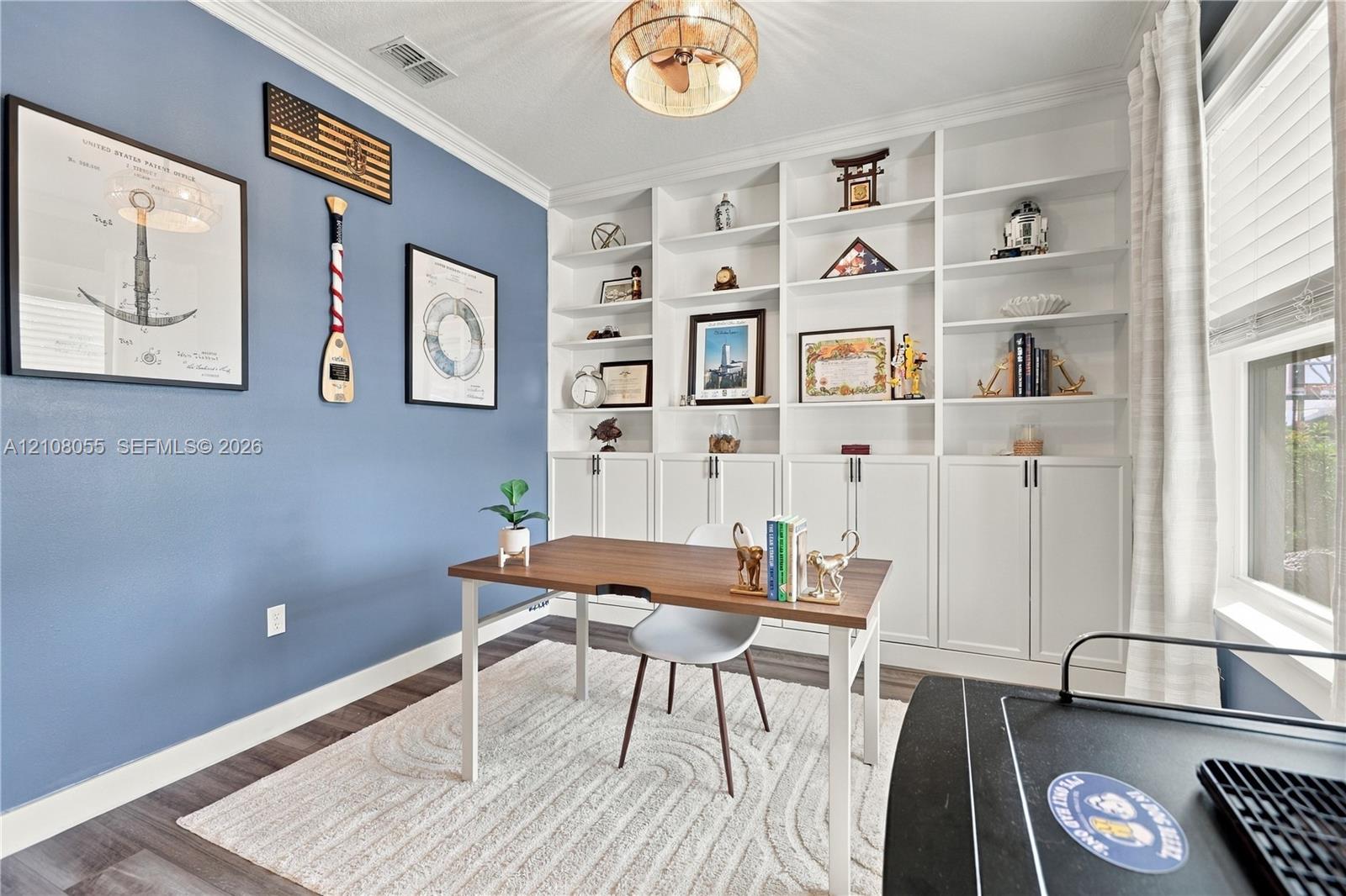 Built-in white floor-to-ceiling shelving and cabinetry, wood-finish flooring, and crown molding