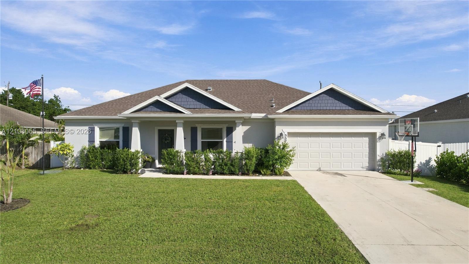 Stucco exterior featuring dual gables with shingle accents, a covered front entryway with square columns, and a concrete driveway