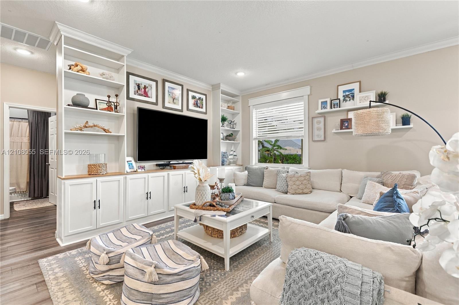 Built-in floor-to-ceiling white cabinetry, wood-finish flooring, recessed lighting, and white floating wall shelves