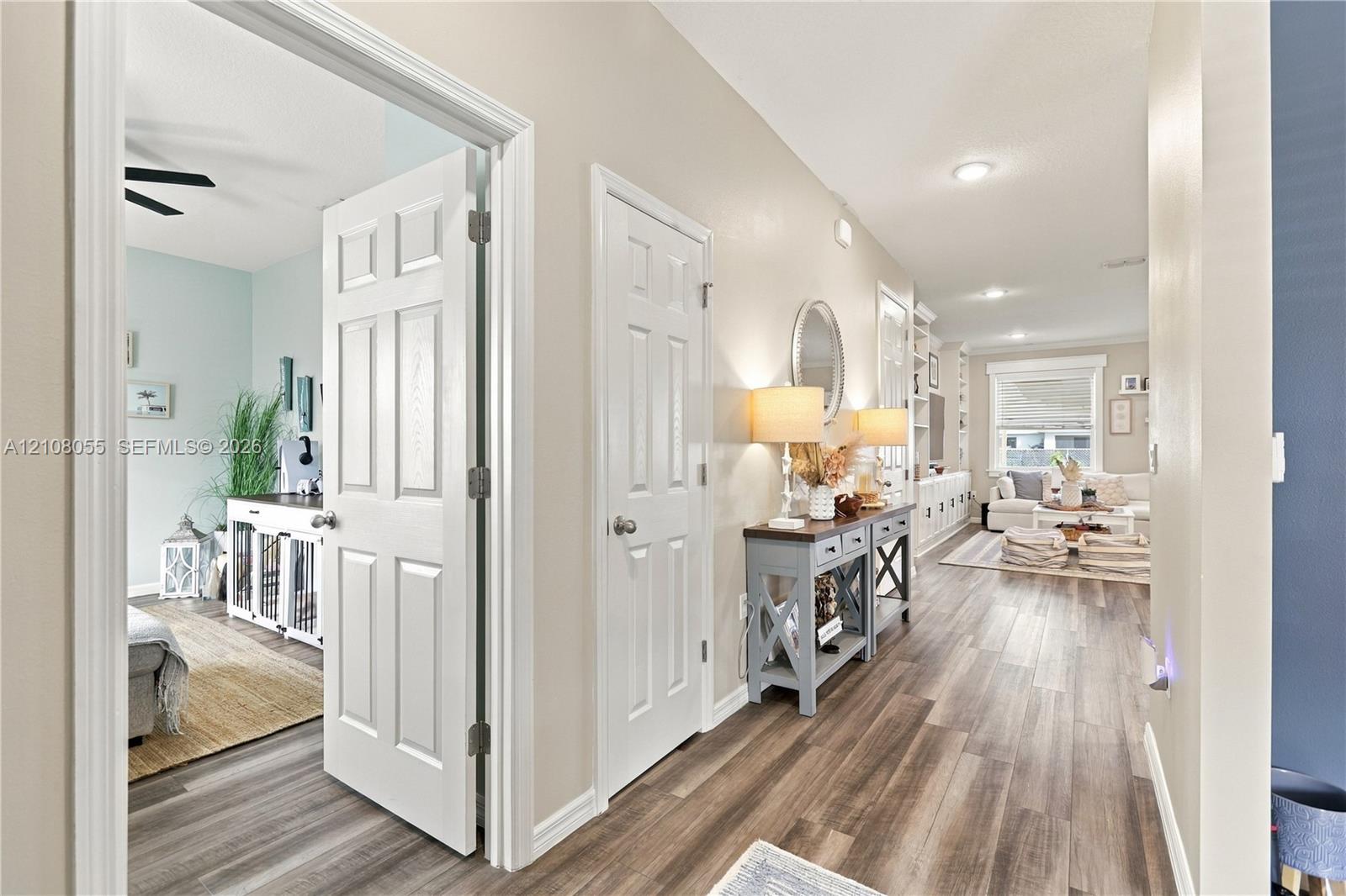 Interior hallway featuring wood-finish flooring, six-panel interior doors, recessed lighting, and built-in wall shelving