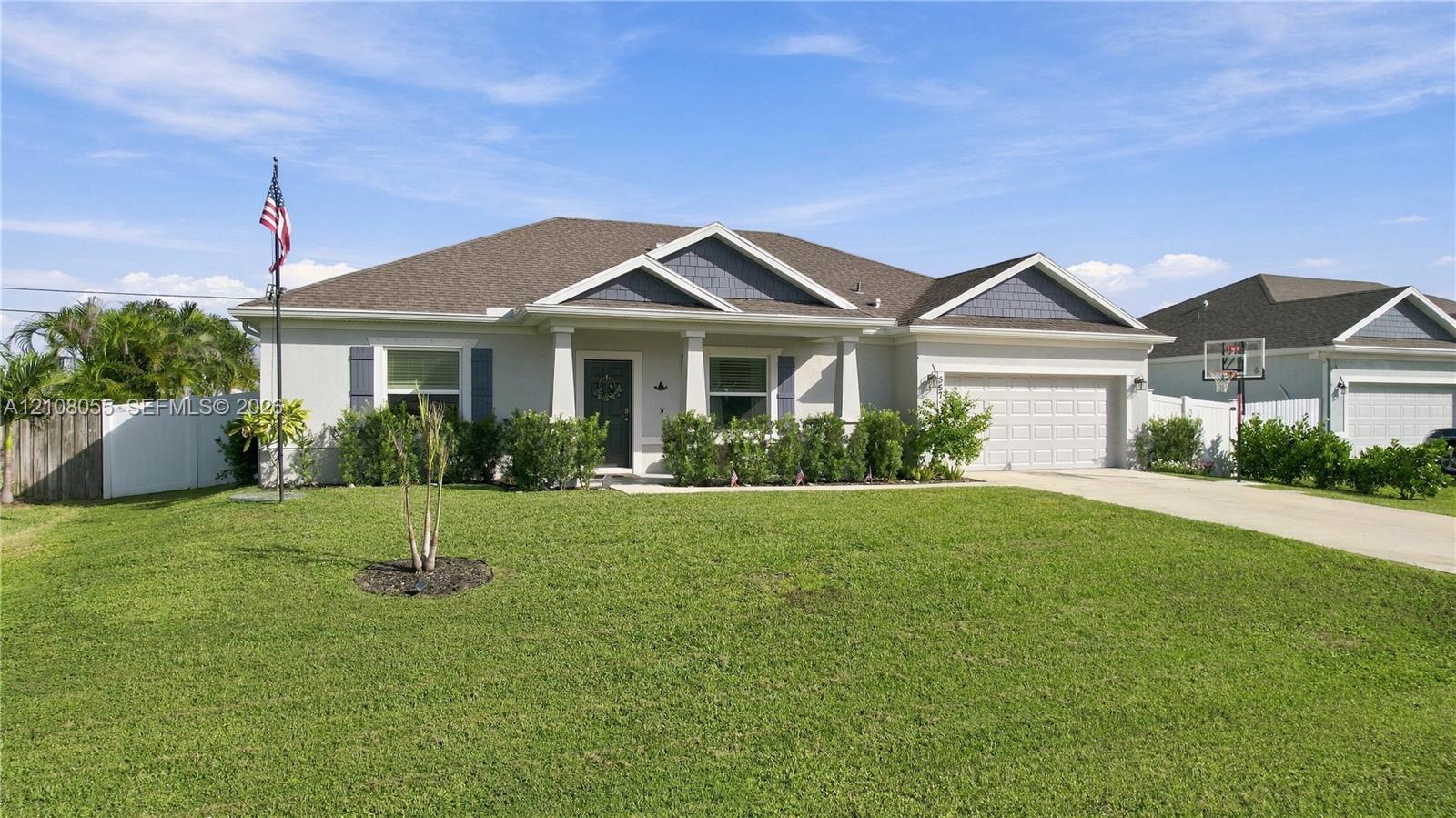 Single-story residence featuring a covered front porch, composite shingle roof, two-car garage, and neutral exterior siding with decorative shutters