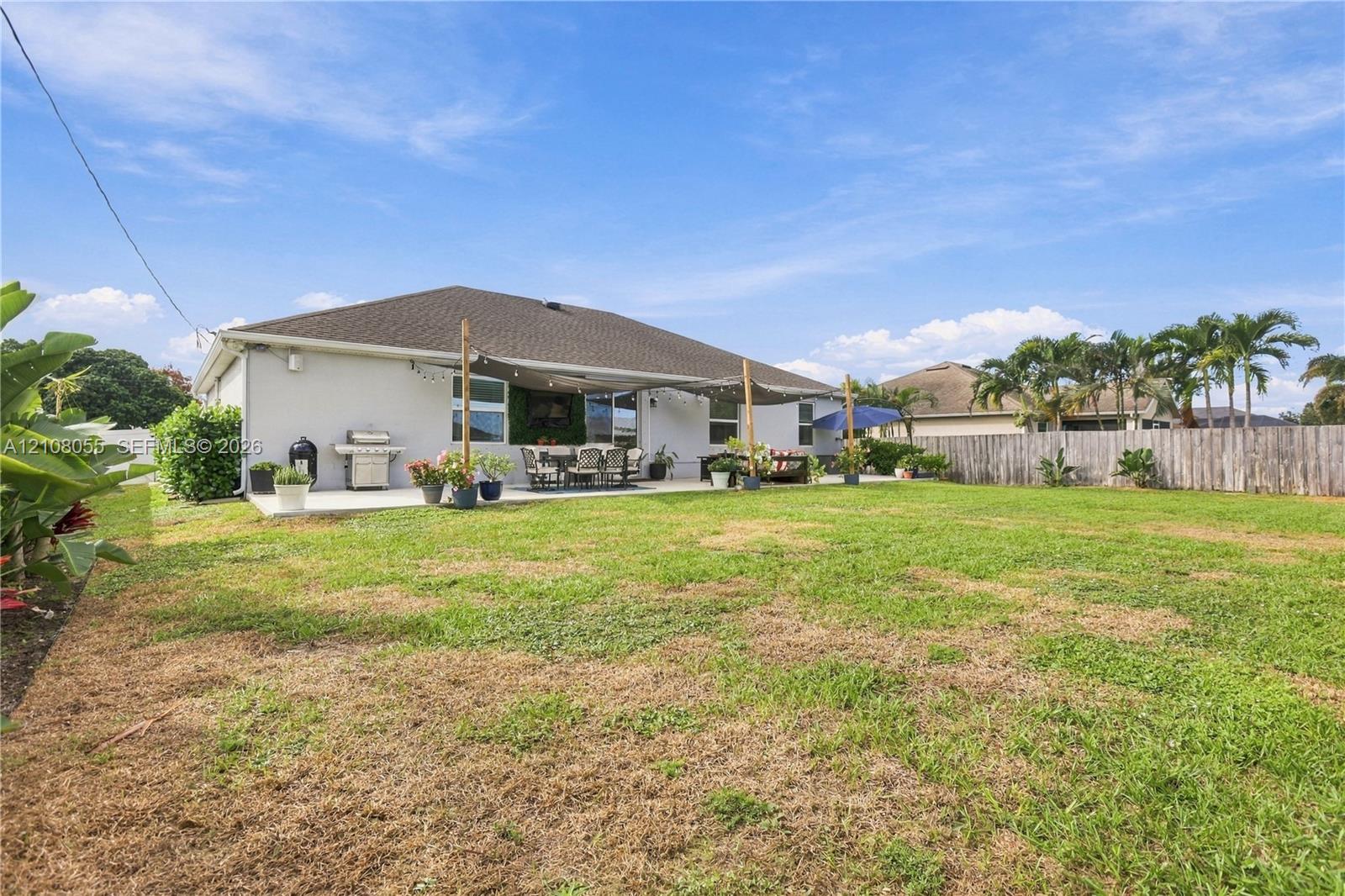 Backyard featuring an expansive lawn, concrete patio, and perimeter wood privacy fencing