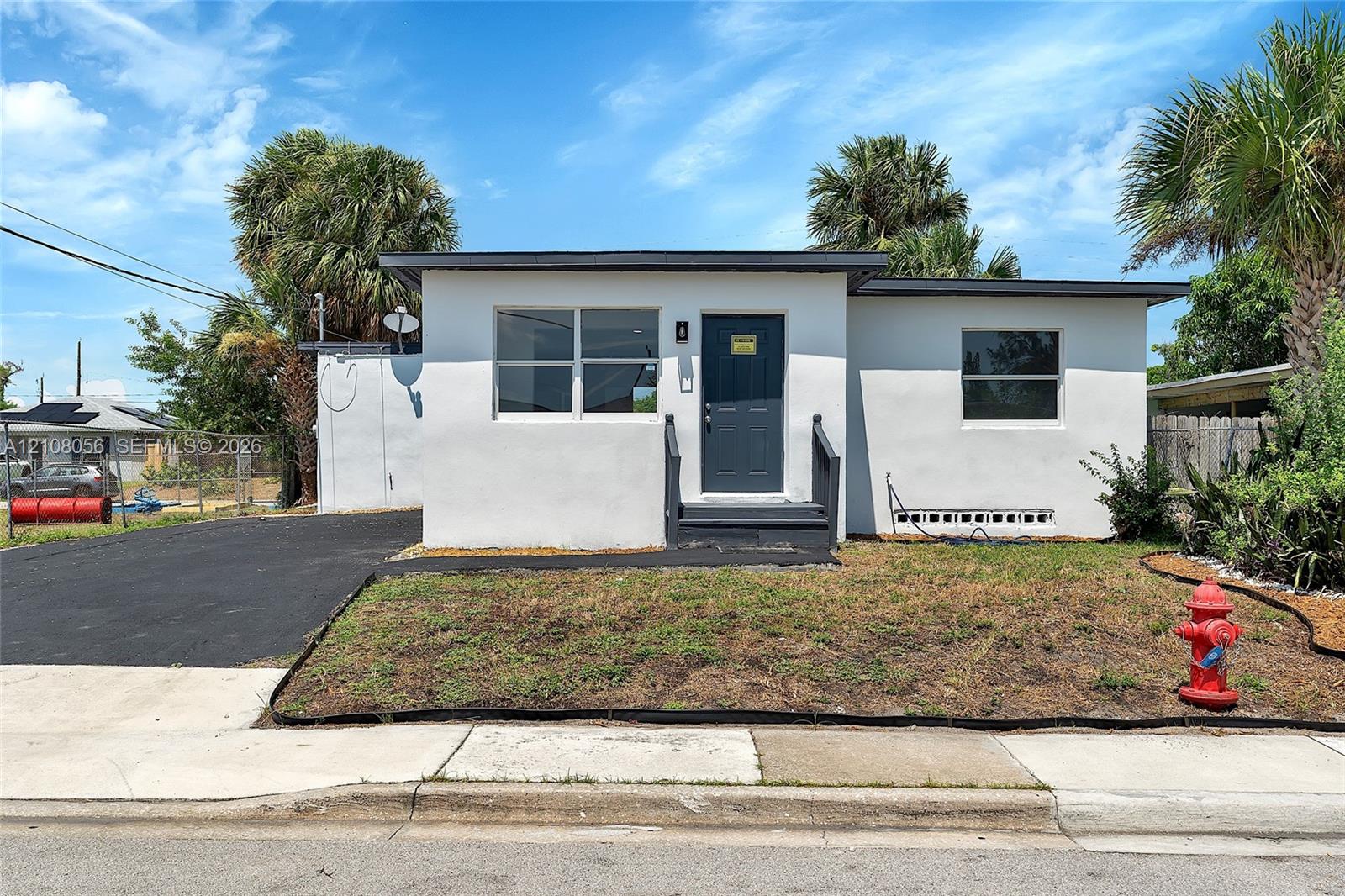 Single-story residence featuring a smooth stucco exterior, asphalt driveway, and metal-trimmed roofline