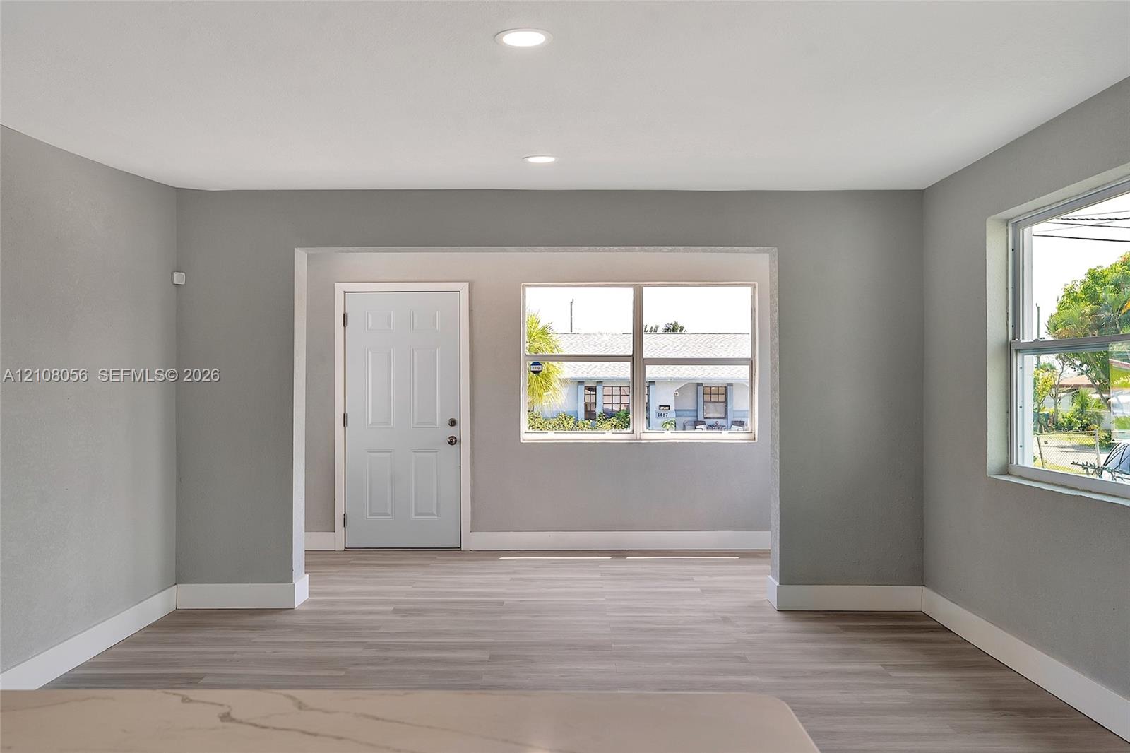 Interior space featuring wood-finish flooring, recessed lighting, neutral wall paint, white trim, and oversized windows