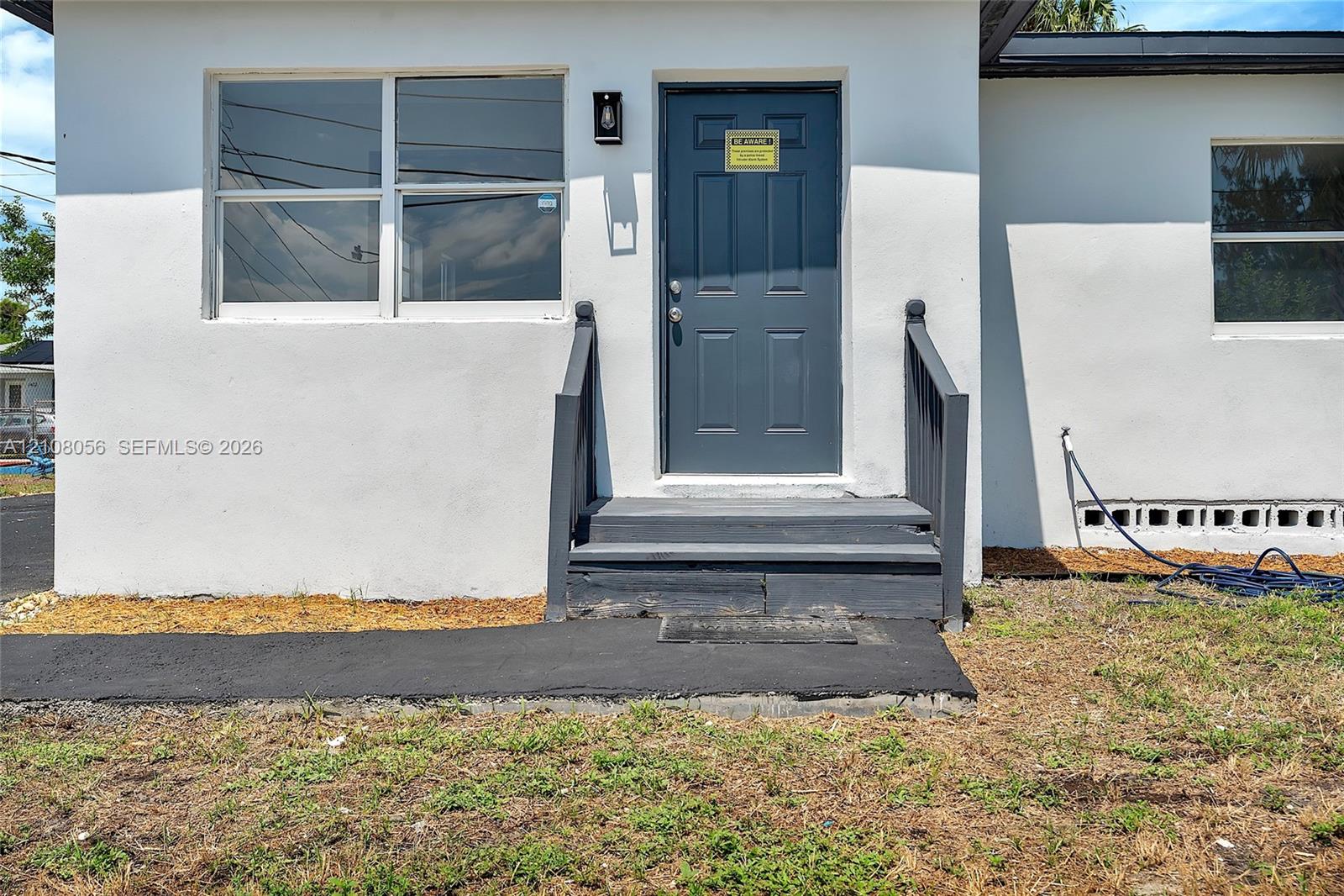 Stucco exterior featuring dual-pane windows, a dark-toned solid front door, and a dedicated walkway with matching painted steps and railings