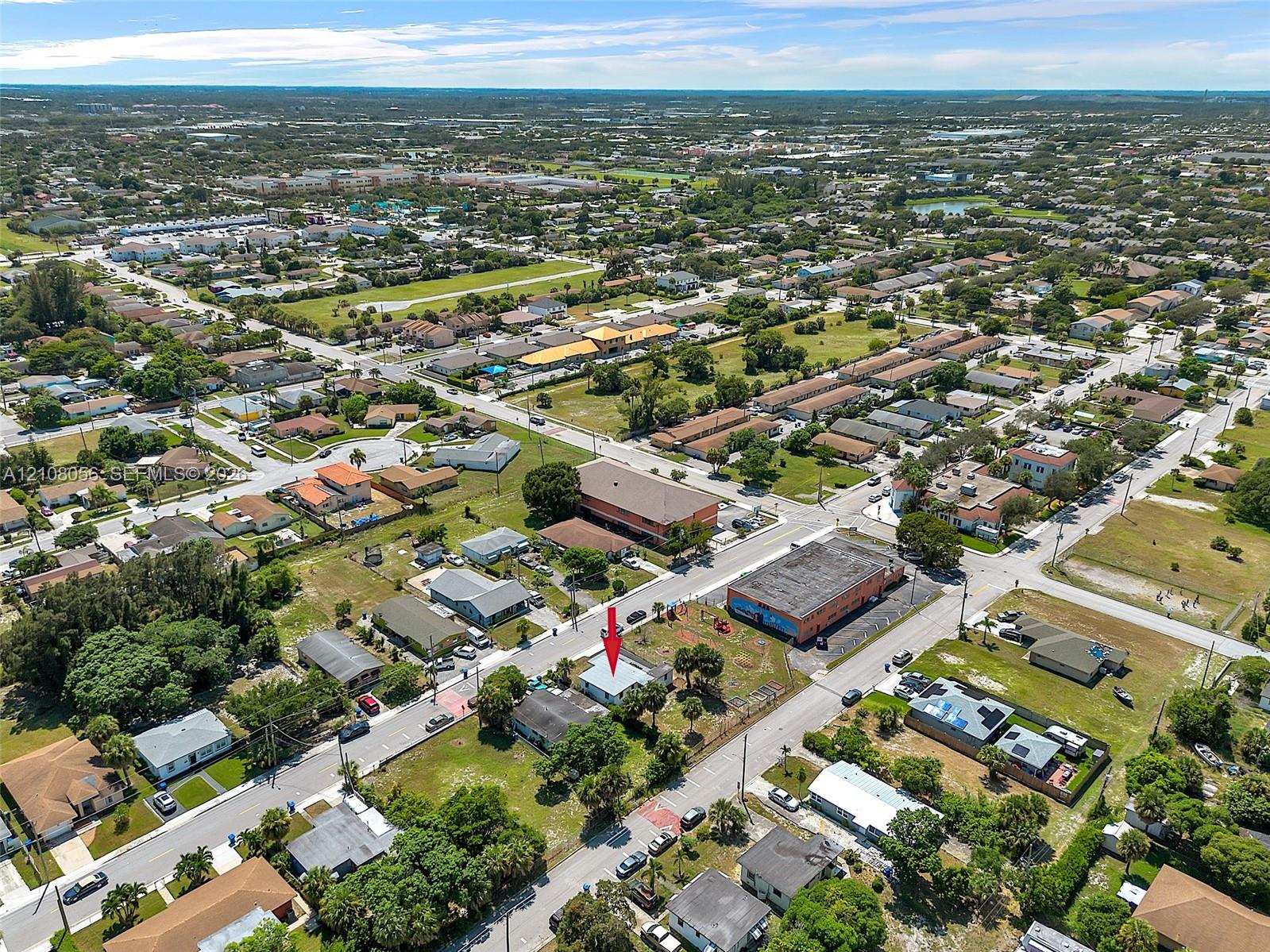 Aerial perspective featuring a corner lot property with established vegetation and street-level access