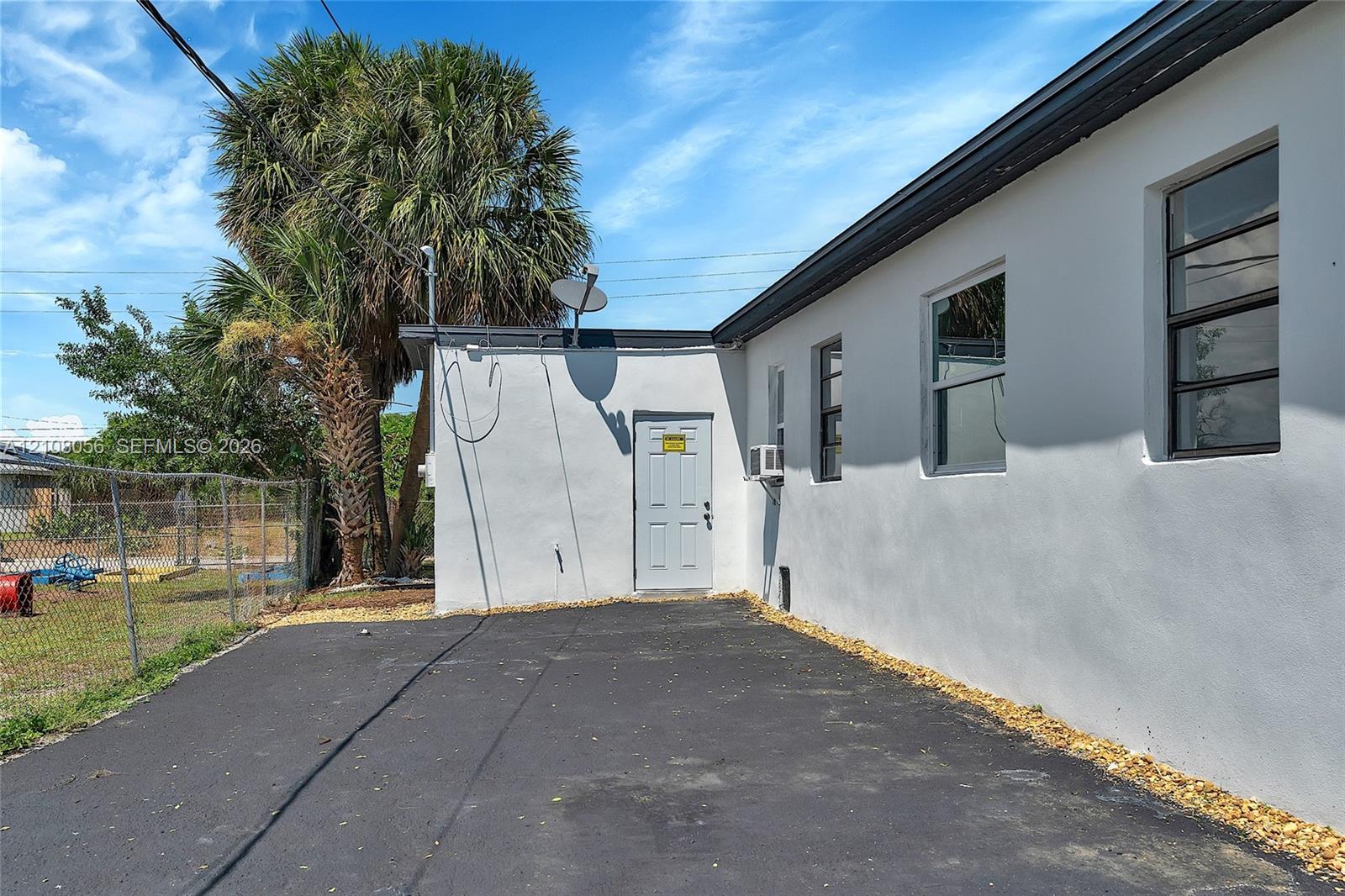 Exterior features include smooth white stucco siding, asphalt paving, and a fenced perimeter