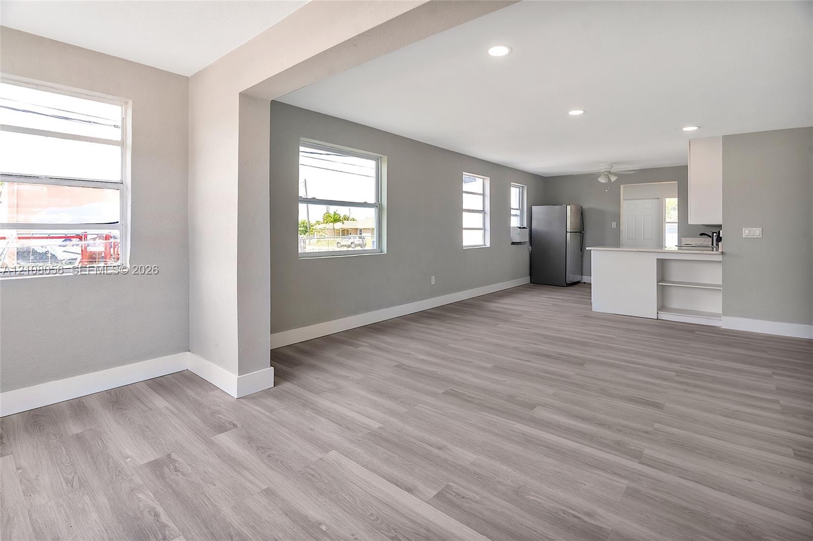 Open-concept interior featuring wood-finish flooring, recessed lighting, neutral wall tones, and a kitchen peninsula with built-in cabinetry