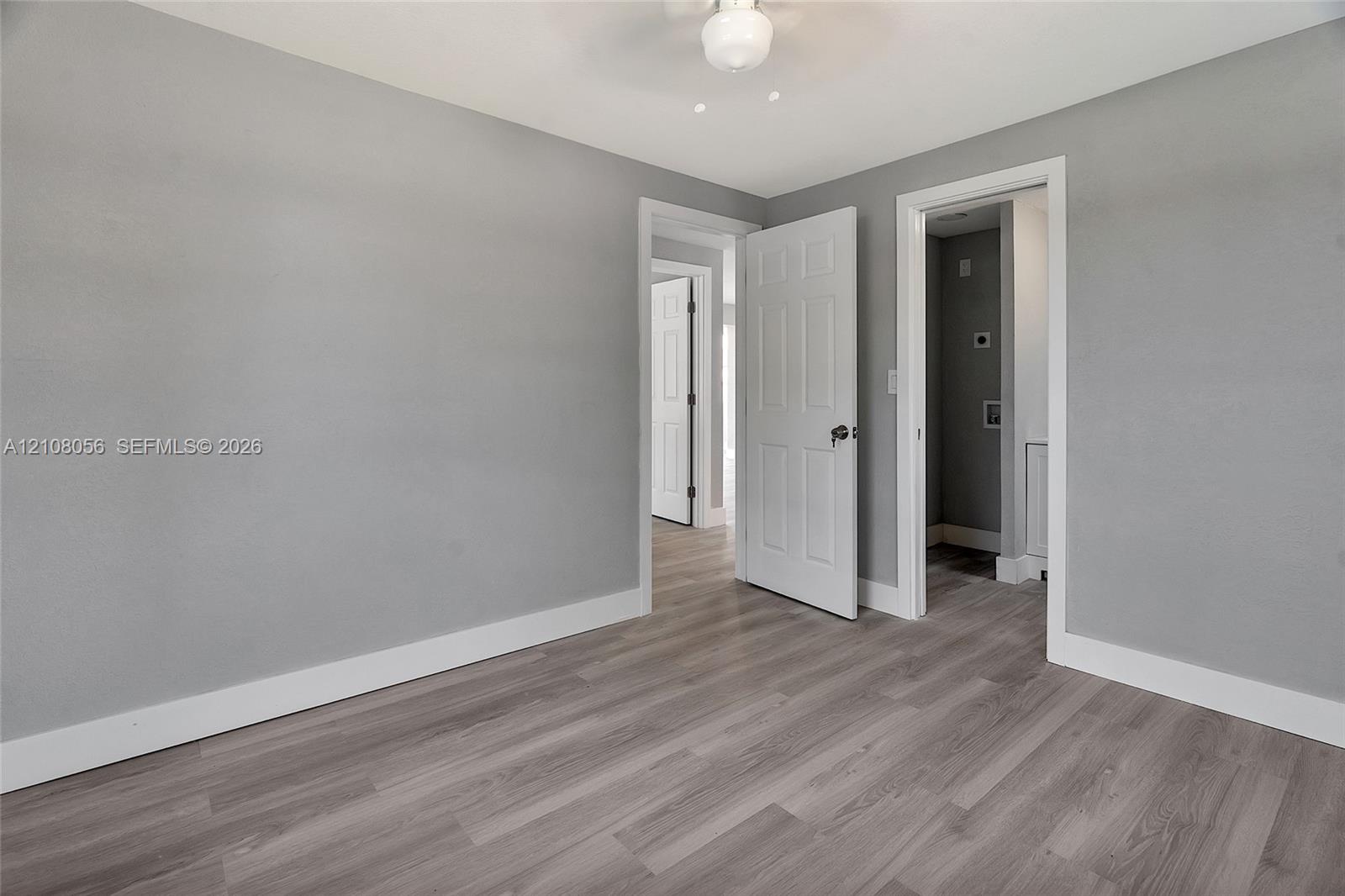 Interior space featuring wood-finish flooring, light gray walls, six-panel interior doors, and a ceiling-mounted light fixture
