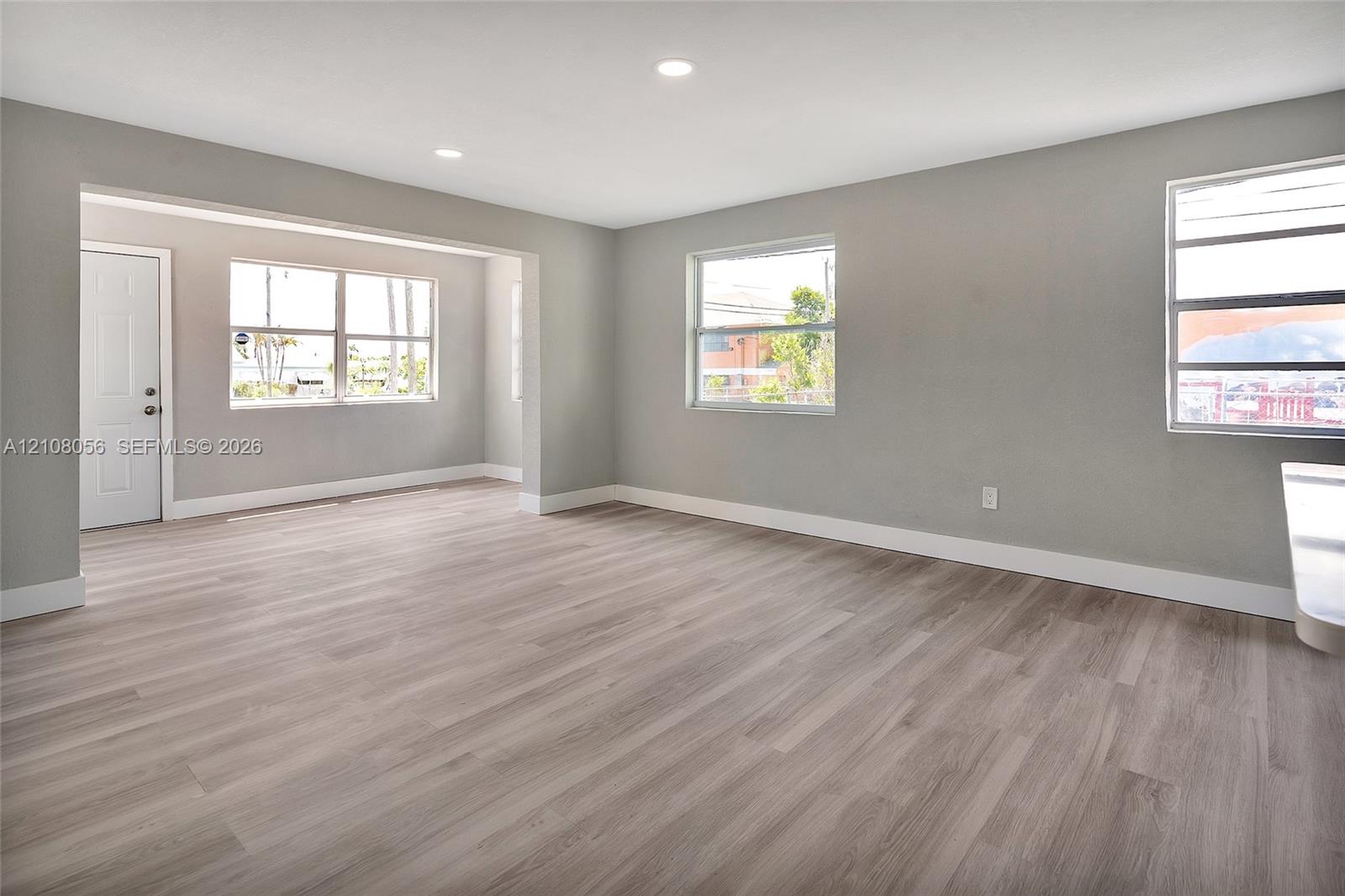 Open-concept interior space featuring light-tone wood-finish flooring, recessed lighting, and multiple horizontal sliding windows