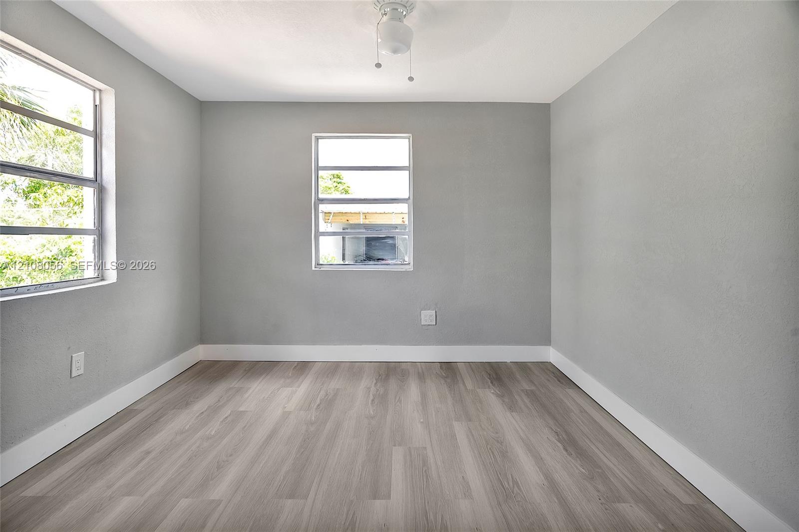 Room featuring wood-finish flooring, two horizontal-pane windows, and a central ceiling light fixture