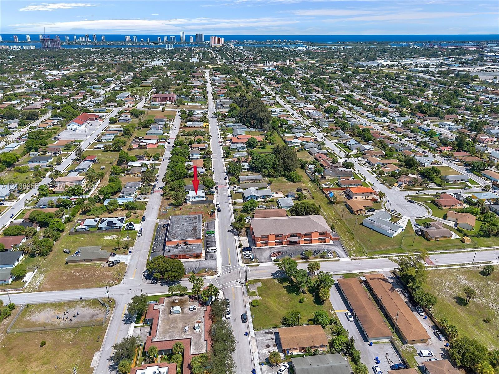 Aerial view of residential property situated in a coastal vicinity featuring paved street access and proximity to regional infrastructure
