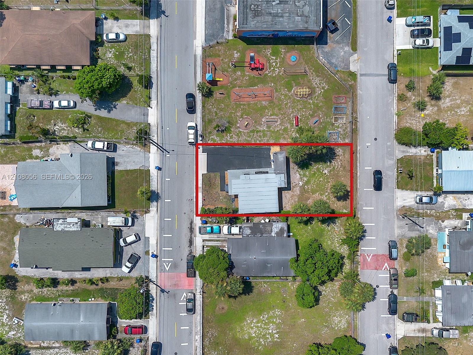 Aerial view of a corner lot featuring an asphalt driveway and perimeter landscaping
