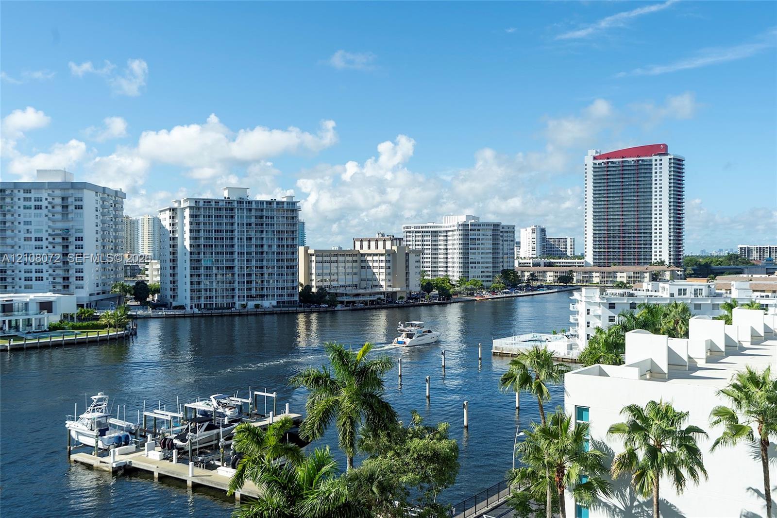 Waterfront setting featuring a private deep-water dock, mature palm trees, and expansive cityscape horizons