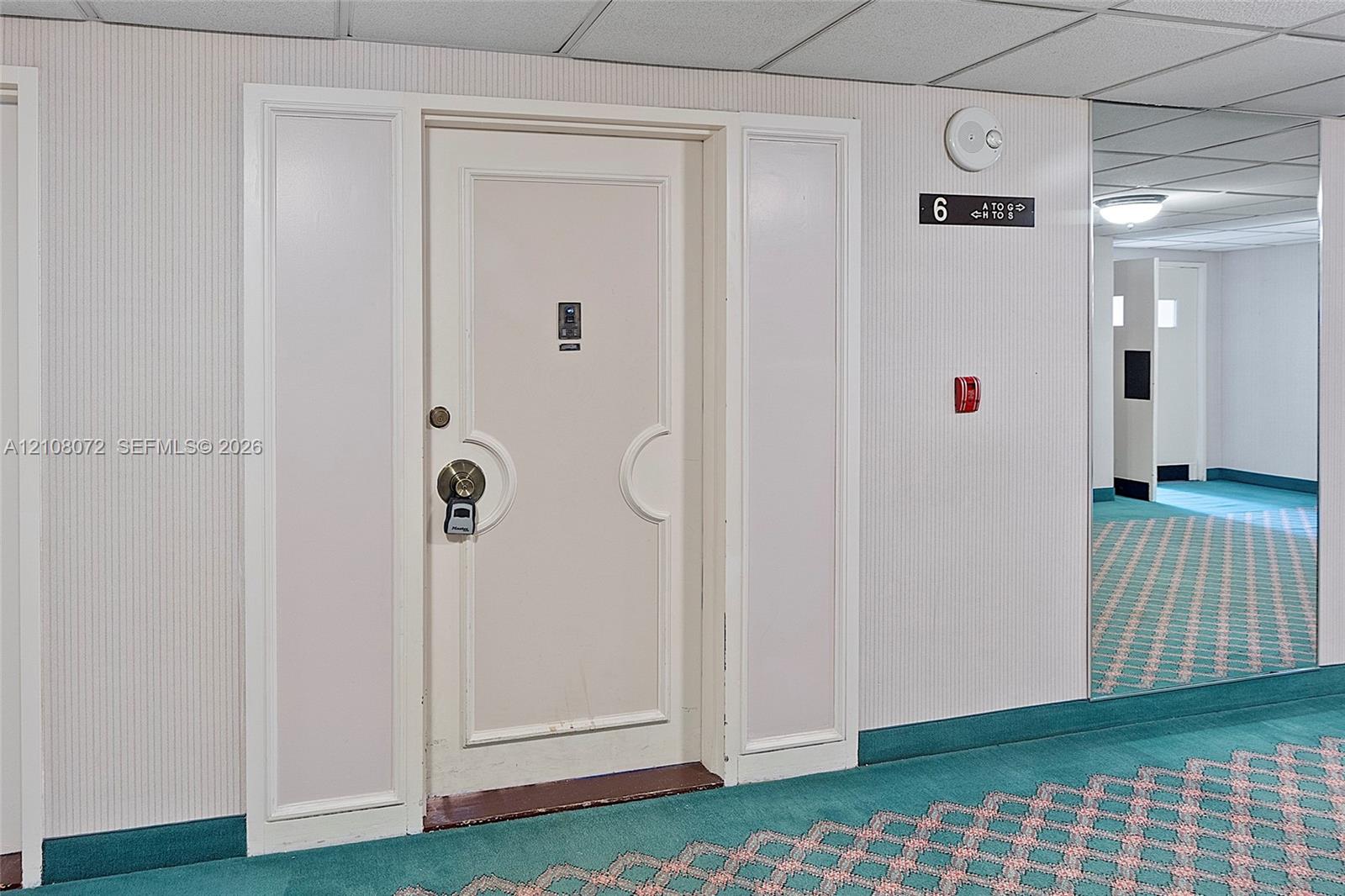 Entry door with dual sidelights, brushed metallic hardware, integrated security feature, and wall-mounted floor signage