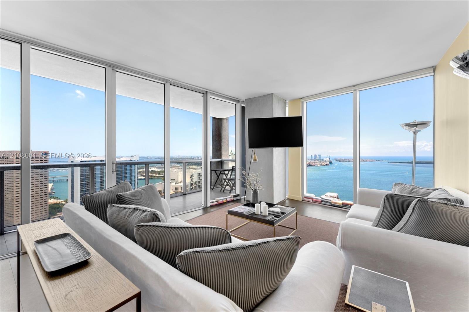 Floor-to-ceiling glass walls, expansive balcony with metal railing, and neutral tile flooring Floor-to-ceiling glass walls, expansive balcony with metal railing, and neutral tile flooring