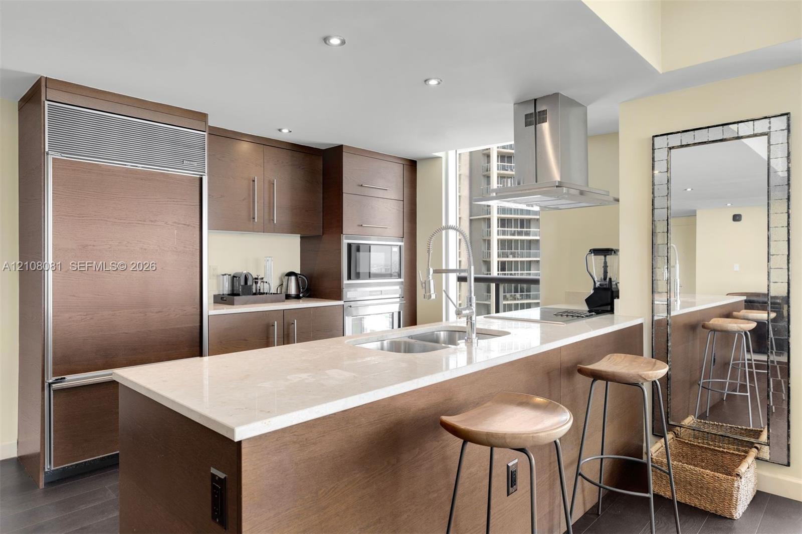 Kitchen featuring wood-finish cabinetry, stone-surface countertops, stainless steel appliances, stainless steel range hood, and recessed lighting
