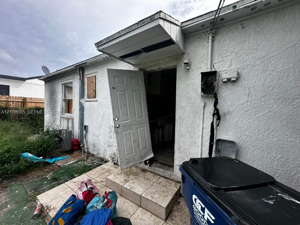 Stucco exterior featuring a paved entry platform and exterior lighting fixture