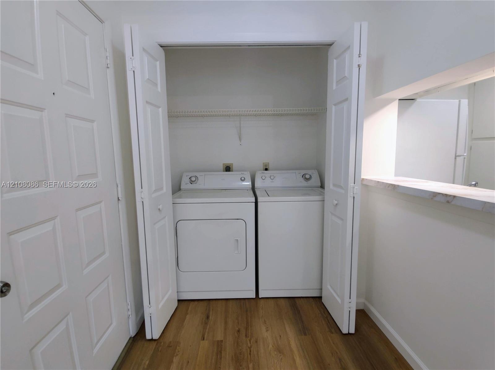 Laundry closet featuring bi-fold doors, overhead wire shelving, and wood-finish flooring