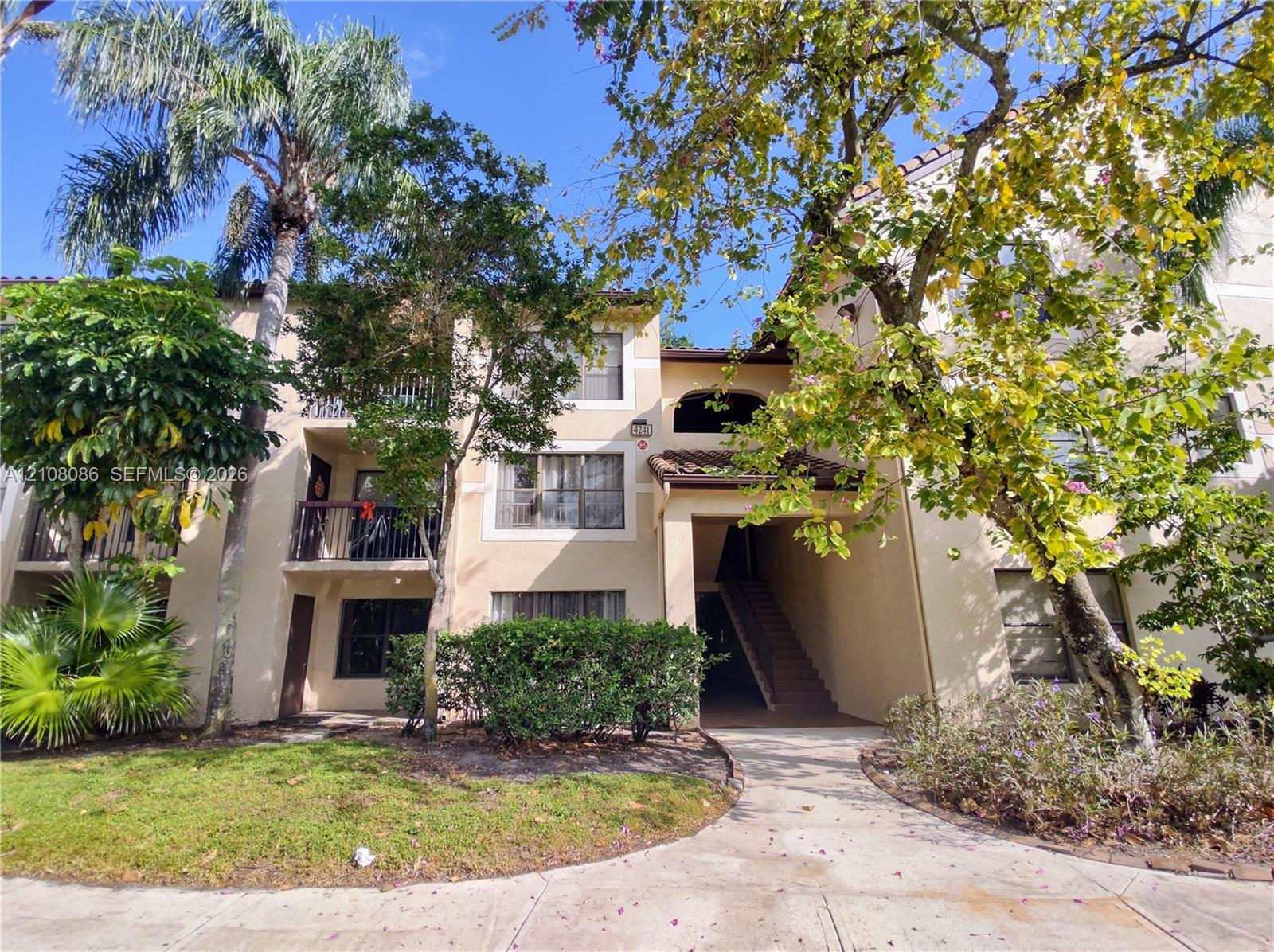Multi-story exterior featuring a stucco facade, clay tile roof accents, private second-story balconies with iron railings, and concrete walkways Multi-story exterior featuring a stucco facade, clay tile roof accents, private second-story balconies with iron railings, and concrete walkways