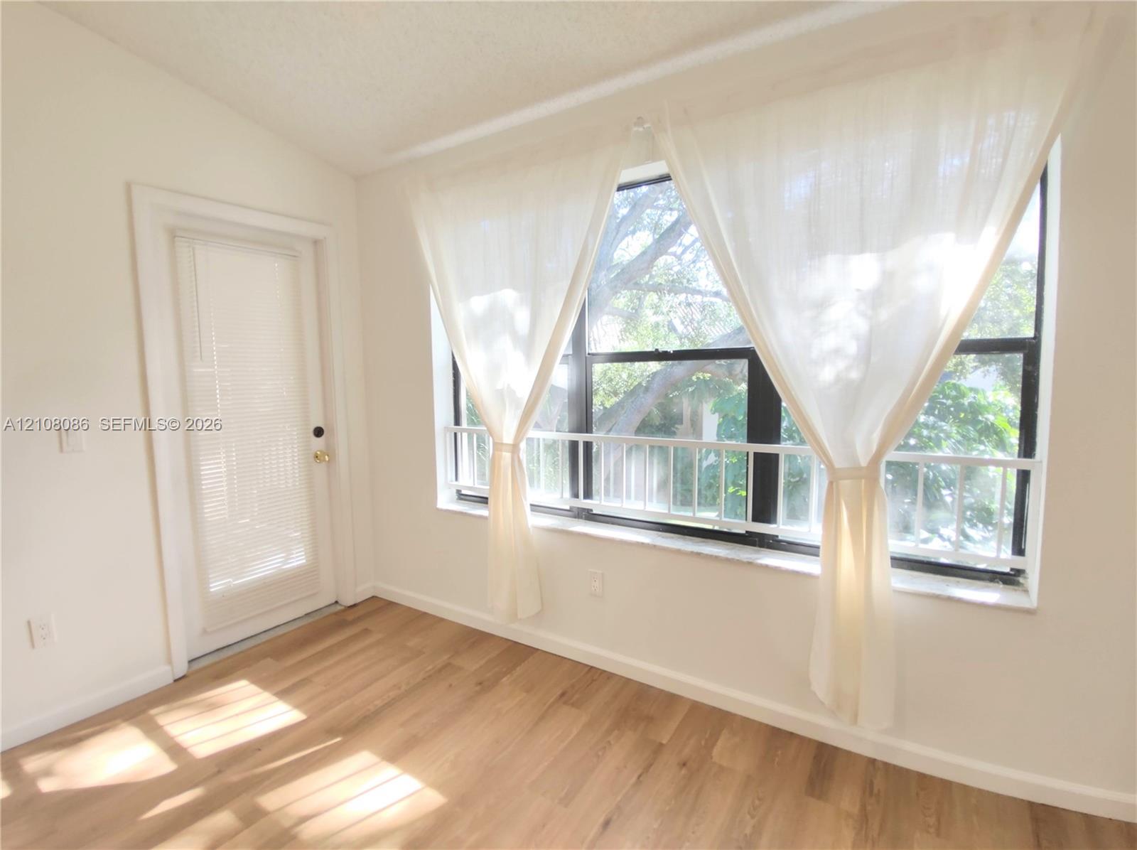 Large windows featuring natural light, wood-finish flooring, and a glass-paneled entry door