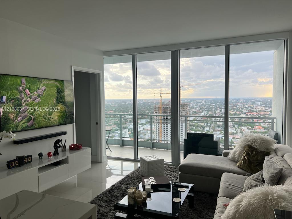 Floor-to-ceiling windows, private balcony, glass panel railing, and polished tile flooring