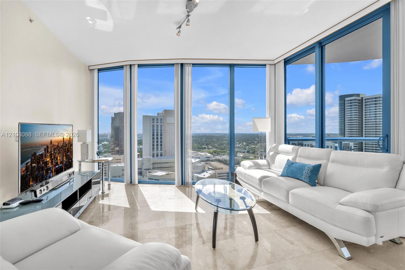 Floor-to-ceiling windows, polished stone flooring, and track lighting