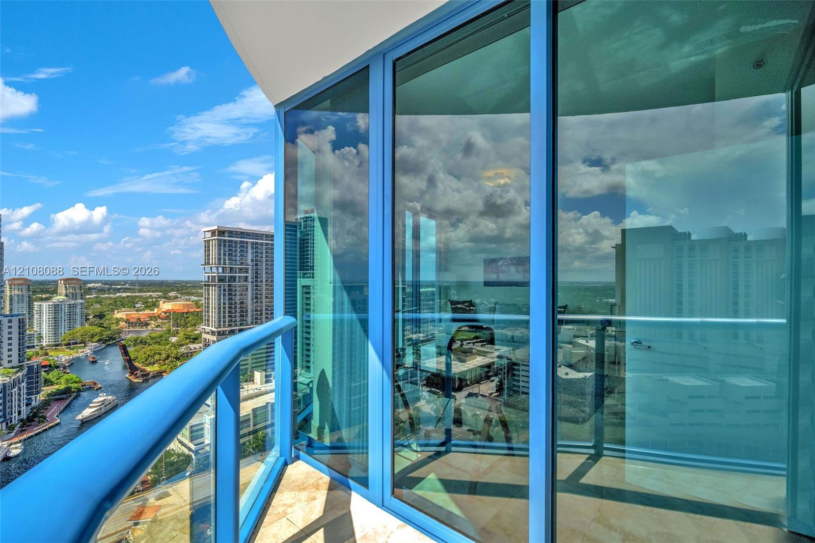 Private balcony featuring floor-to-ceiling glass paneling, metal railings, and stone-tile flooring