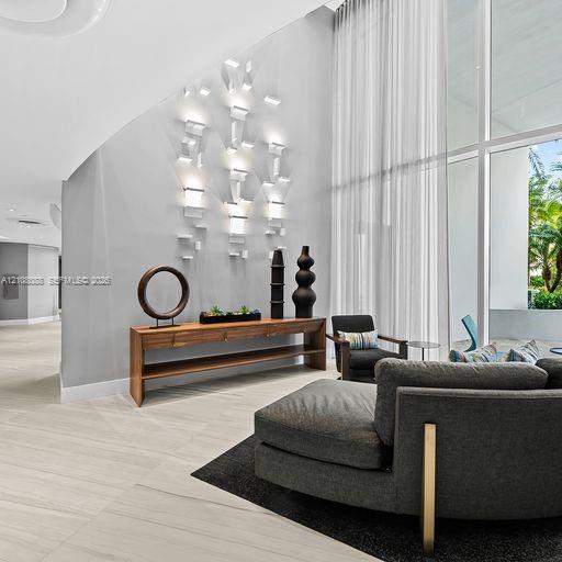 Double-height floor-to-ceiling windows, custom geometric wall-mounted lighting, and large-format porcelain tile flooring