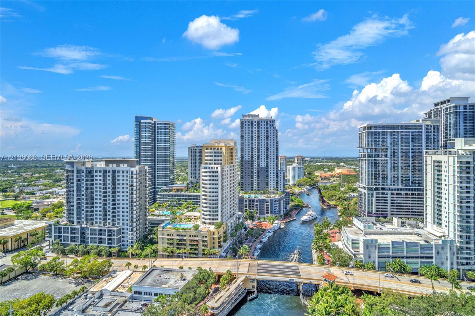Aerial perspective featuring an urban skyline, high-rise architecture, a waterway, and bridges