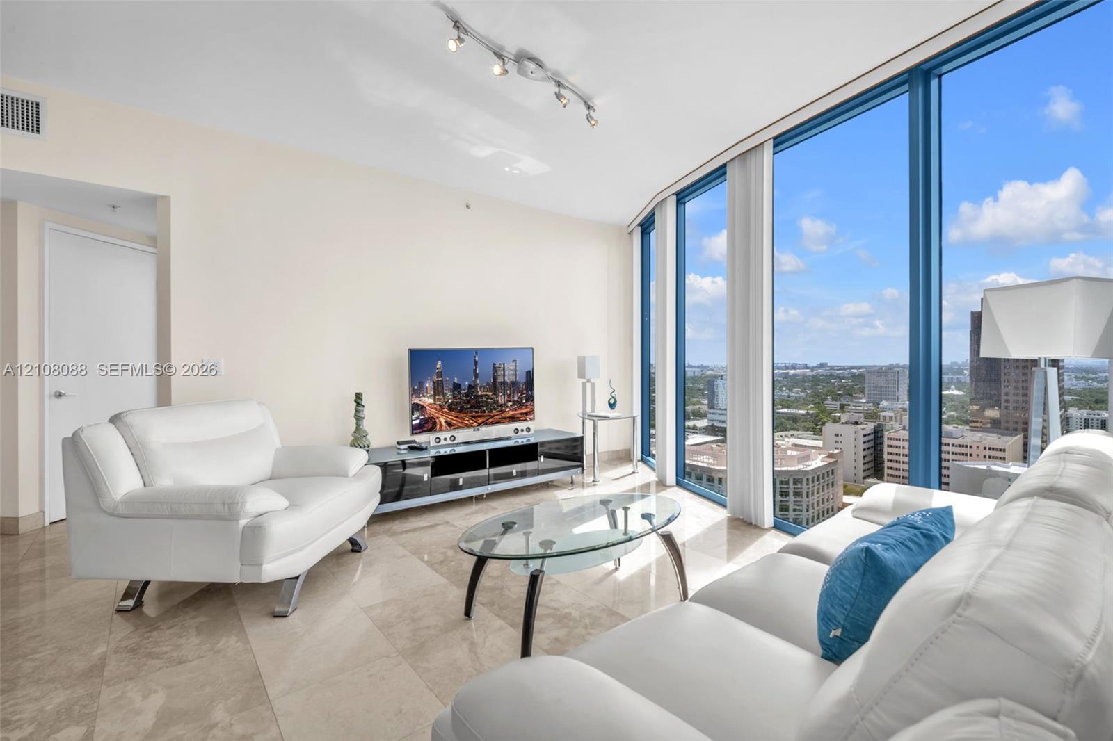 Floor-to-ceiling windows with panoramic urban exposure, polished stone tile flooring, and adjustable track lighting