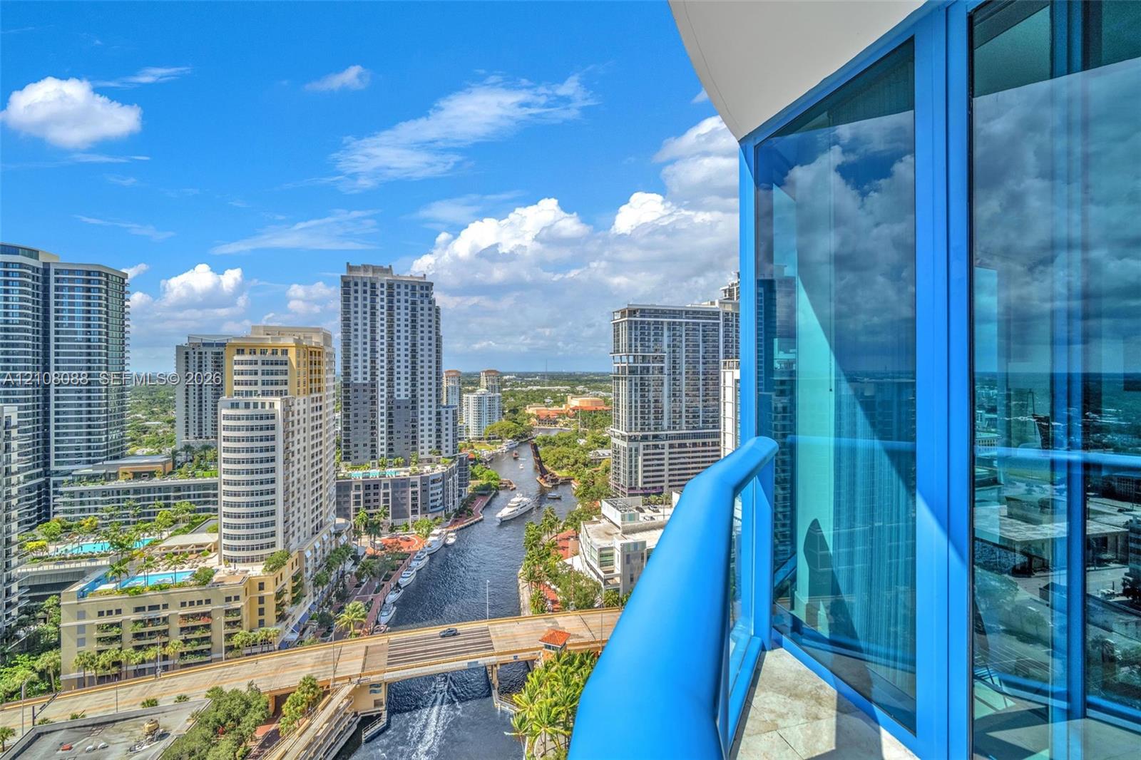 Private balcony with blue glass railing featuring floor-to-ceiling blue-tinted windows and stone-tiled flooring Private balcony with blue glass railing featuring floor-to-ceiling blue-tinted windows and stone-tiled flooring