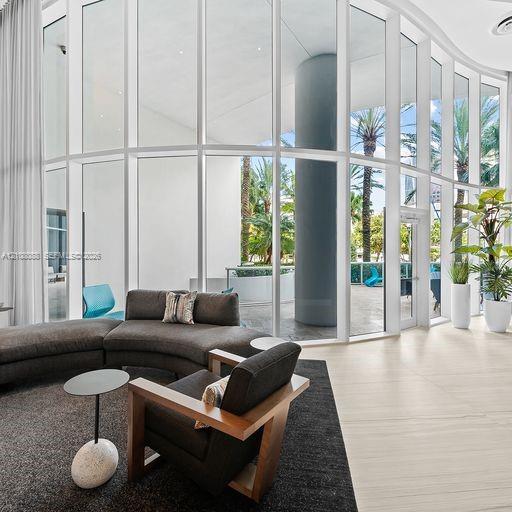 Curved floor-to-ceiling glass wall, light-toned stone tile flooring, and integrated structural column