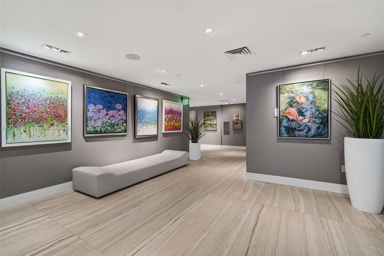 Neutral-toned interior hall featuring wood-finish flooring, recessed lighting, and wall-mounted art hanging systems