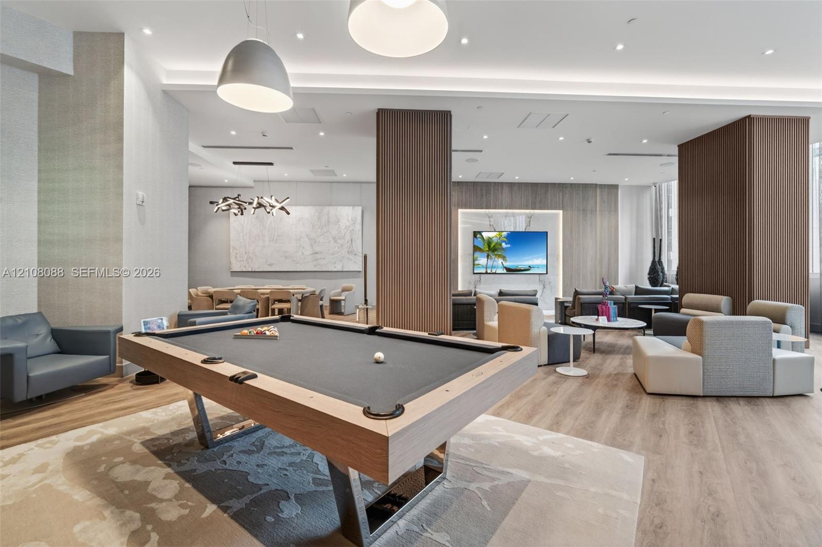 Common area featuring wood-finish flooring, recessed lighting, wood-paneled accent columns, and a built-in television wall feature