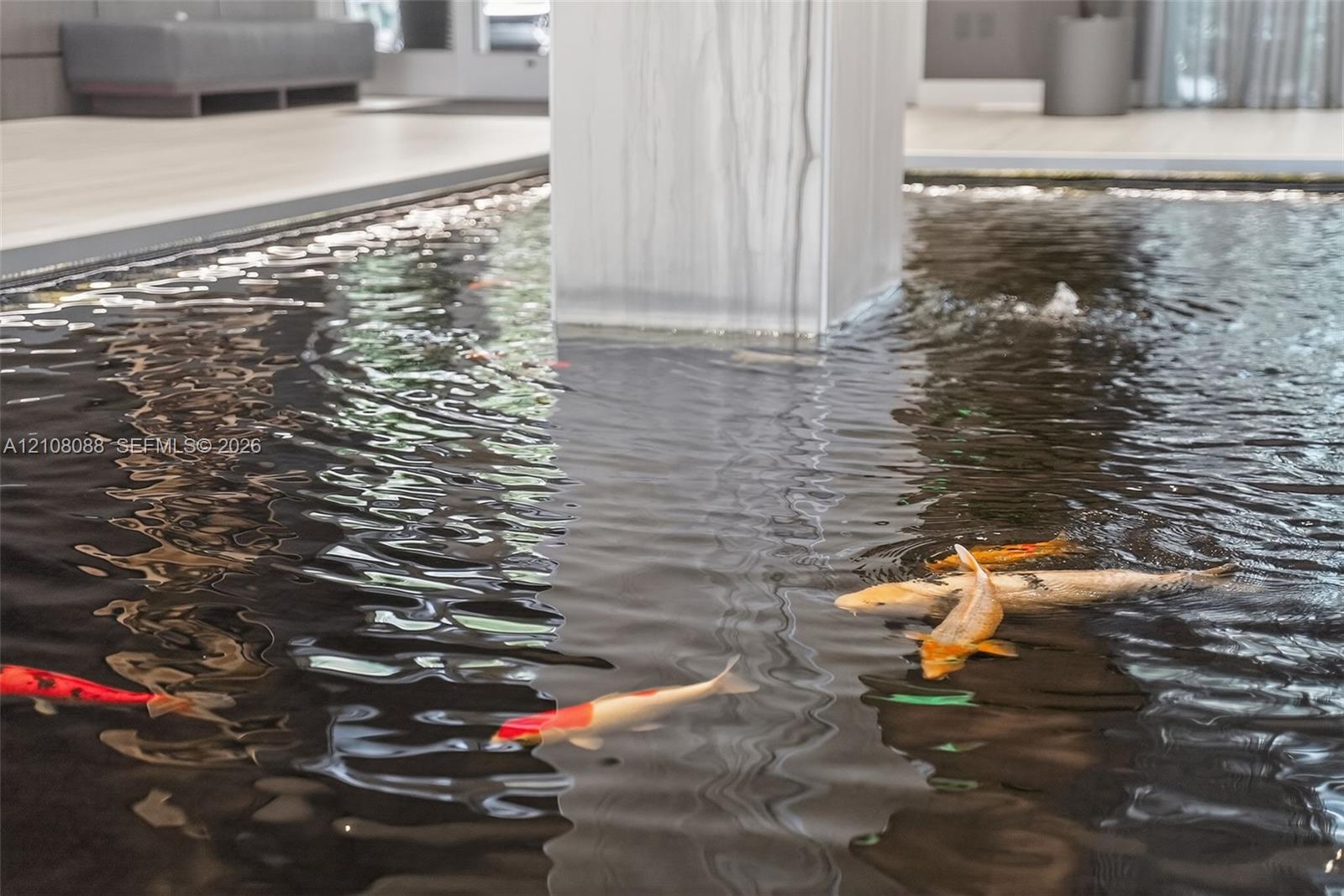 Indoor water feature with koi, stone-finish column, and light-toned flooring