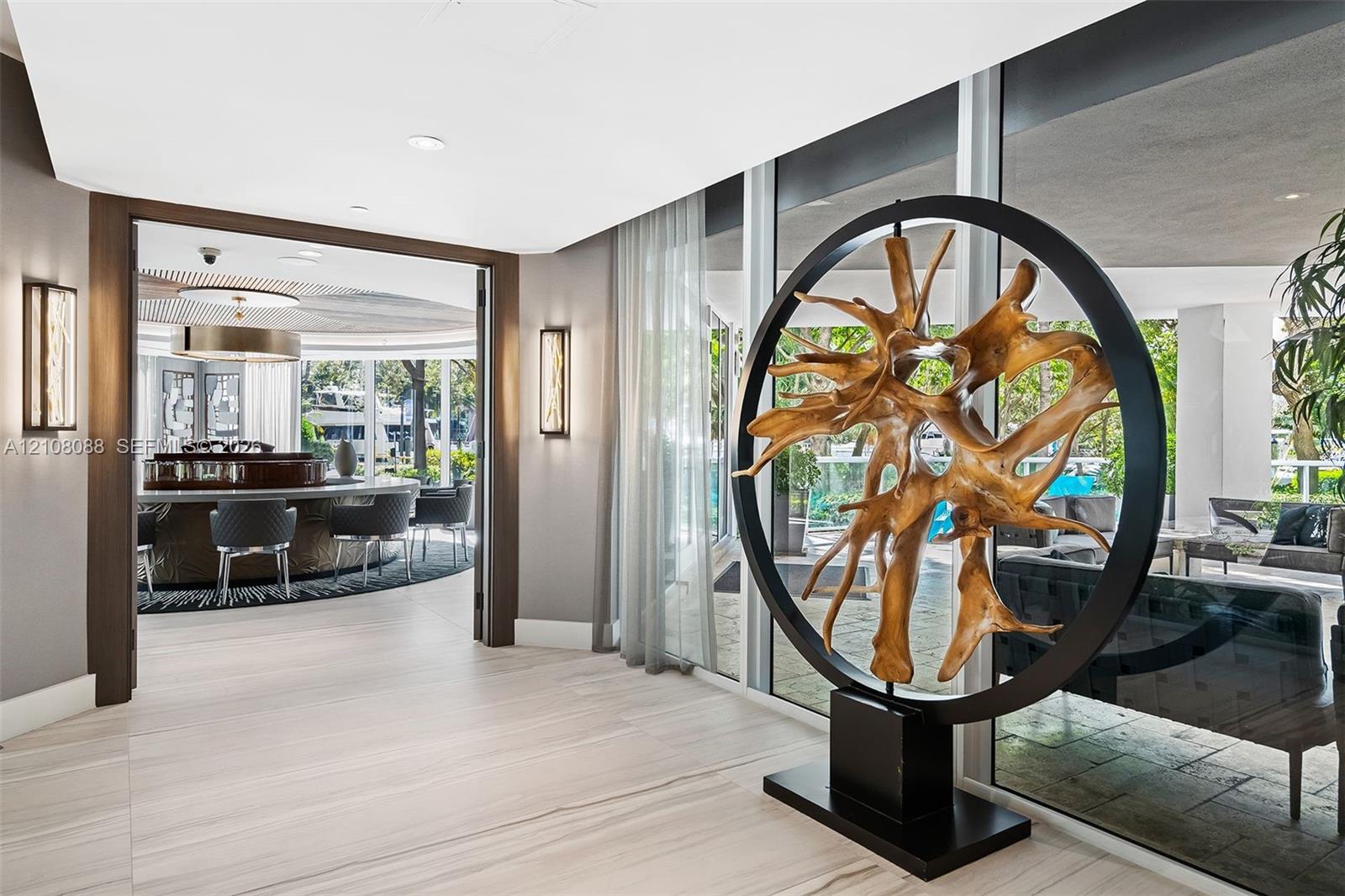 Neutral-toned stone tile flooring, floor-to-ceiling glass wall panels, recessed lighting, and rectangular wall-mounted light fixtures with metallic trim