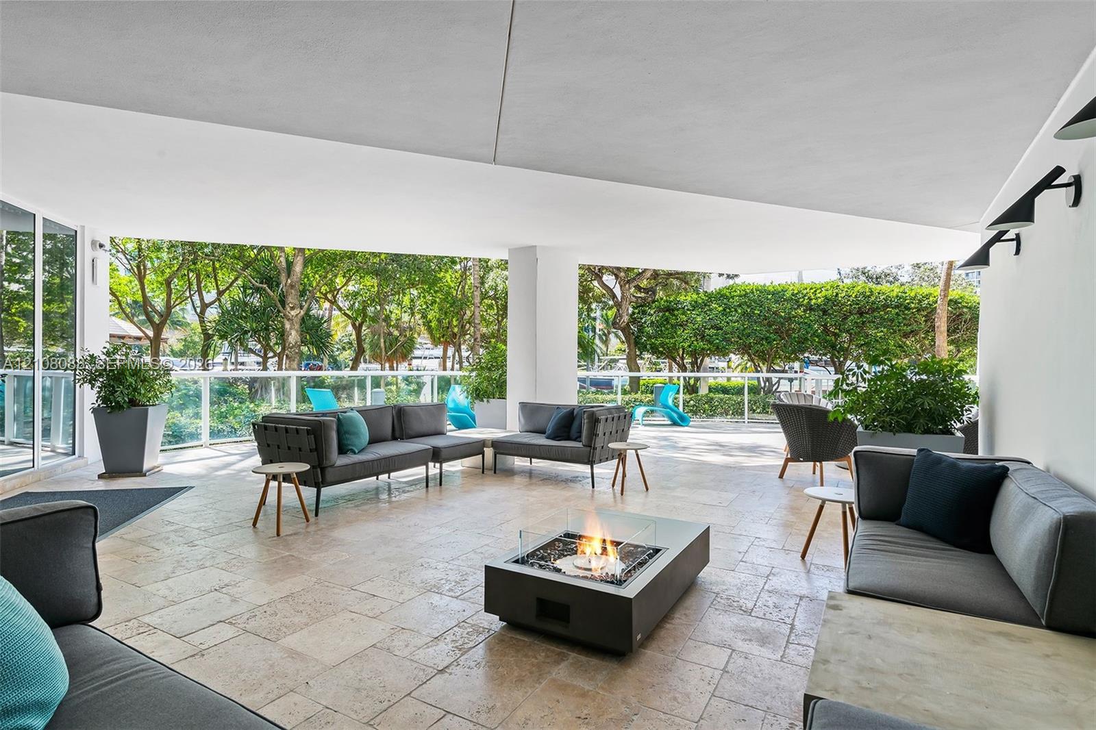 Covered terrace featuring natural stone flooring, glass panel railings, and wall-mounted exterior lighting