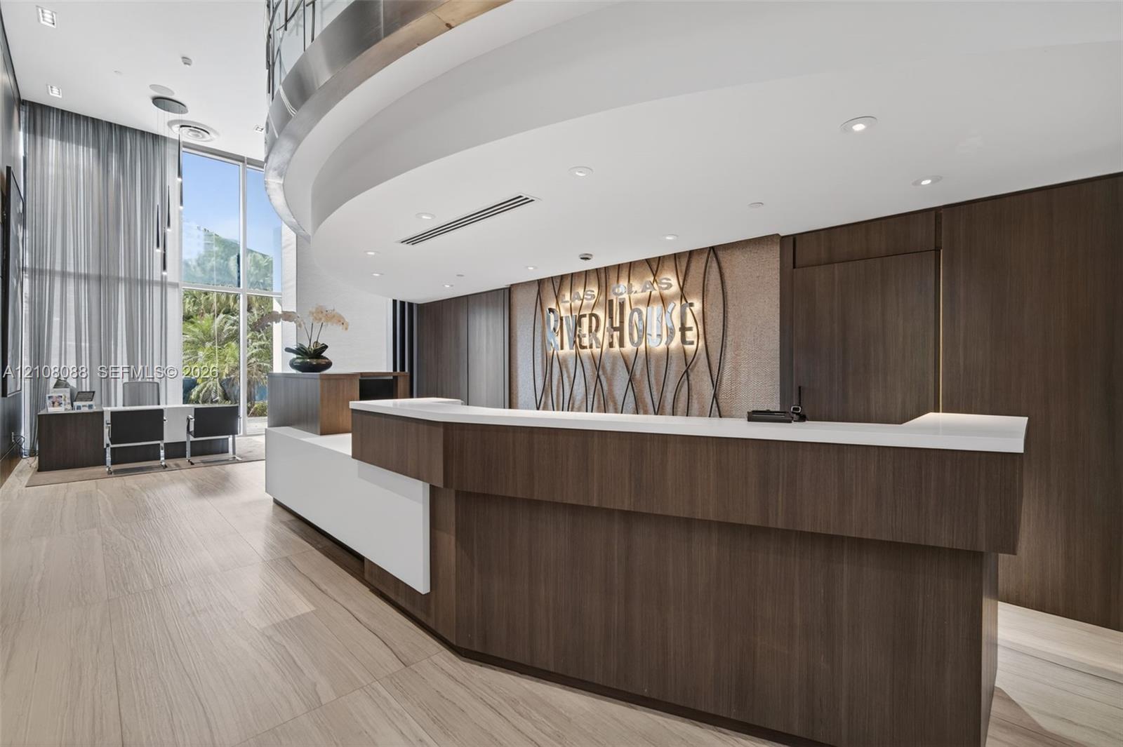 Reception area featuring a curved reception desk with wood-finish cabinetry, a solid surface countertop, recessed ceiling lighting, floor-to-ceiling windows, and wood-finish tile flooring