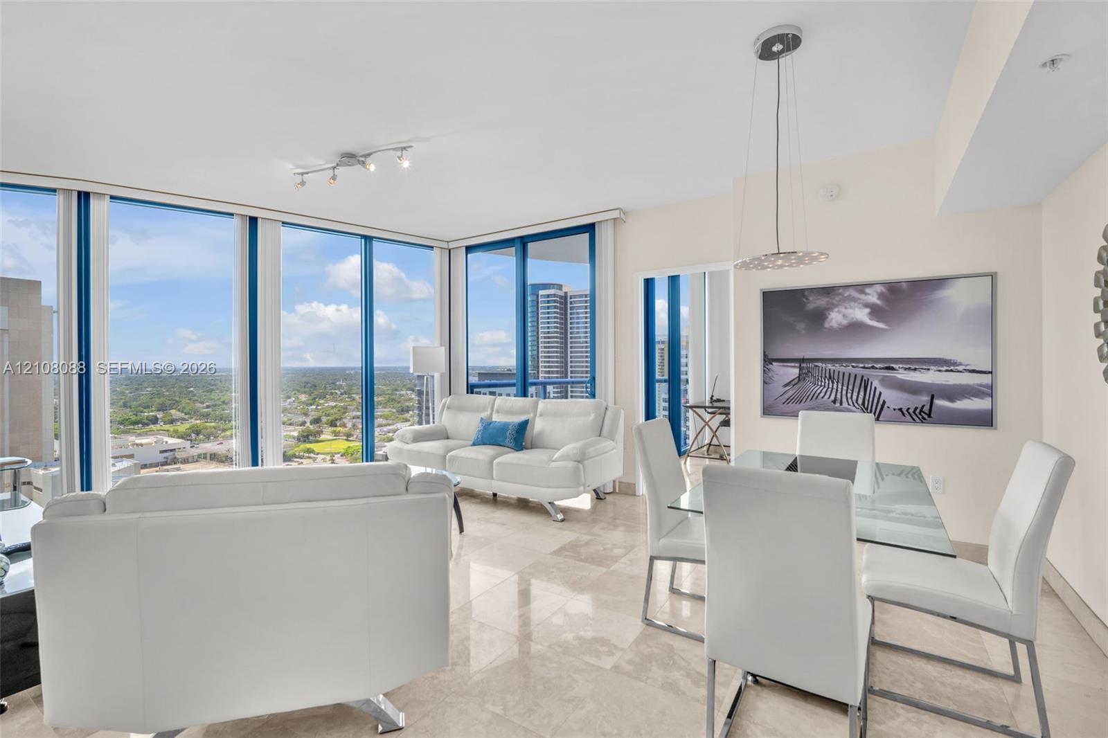Open-concept space featuring floor-to-ceiling windows, polished stone flooring, and suspended pendant lighting Open-concept space featuring floor-to-ceiling windows, polished stone flooring, and suspended pendant lighting