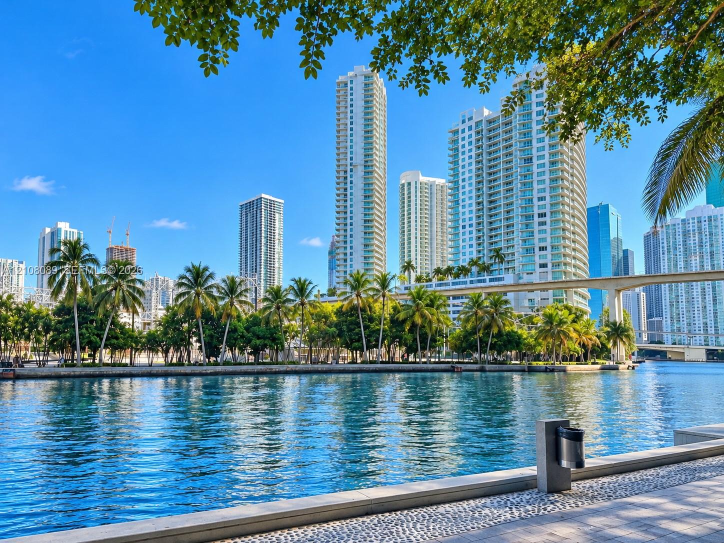 Waterfront concrete promenade featuring pebble-stone paving and mature palm trees