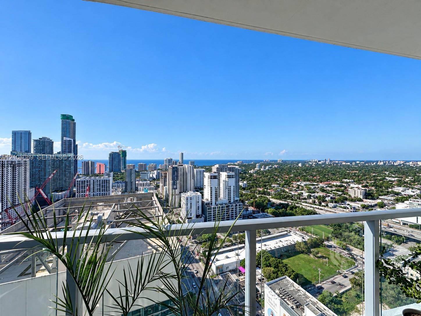 Covered balcony with a glass and metal railing offering panoramic urban and coastal scenery