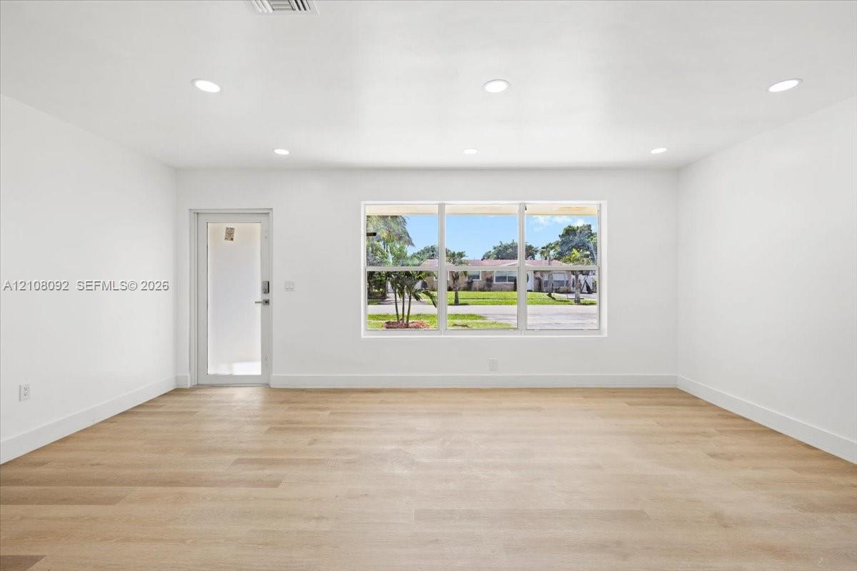 AI Image Open-concept kitchen and living area featuring wood-finish flooring, a waterfall-edge kitchen island, stainless steel range hood, recessed lighting, and large windows