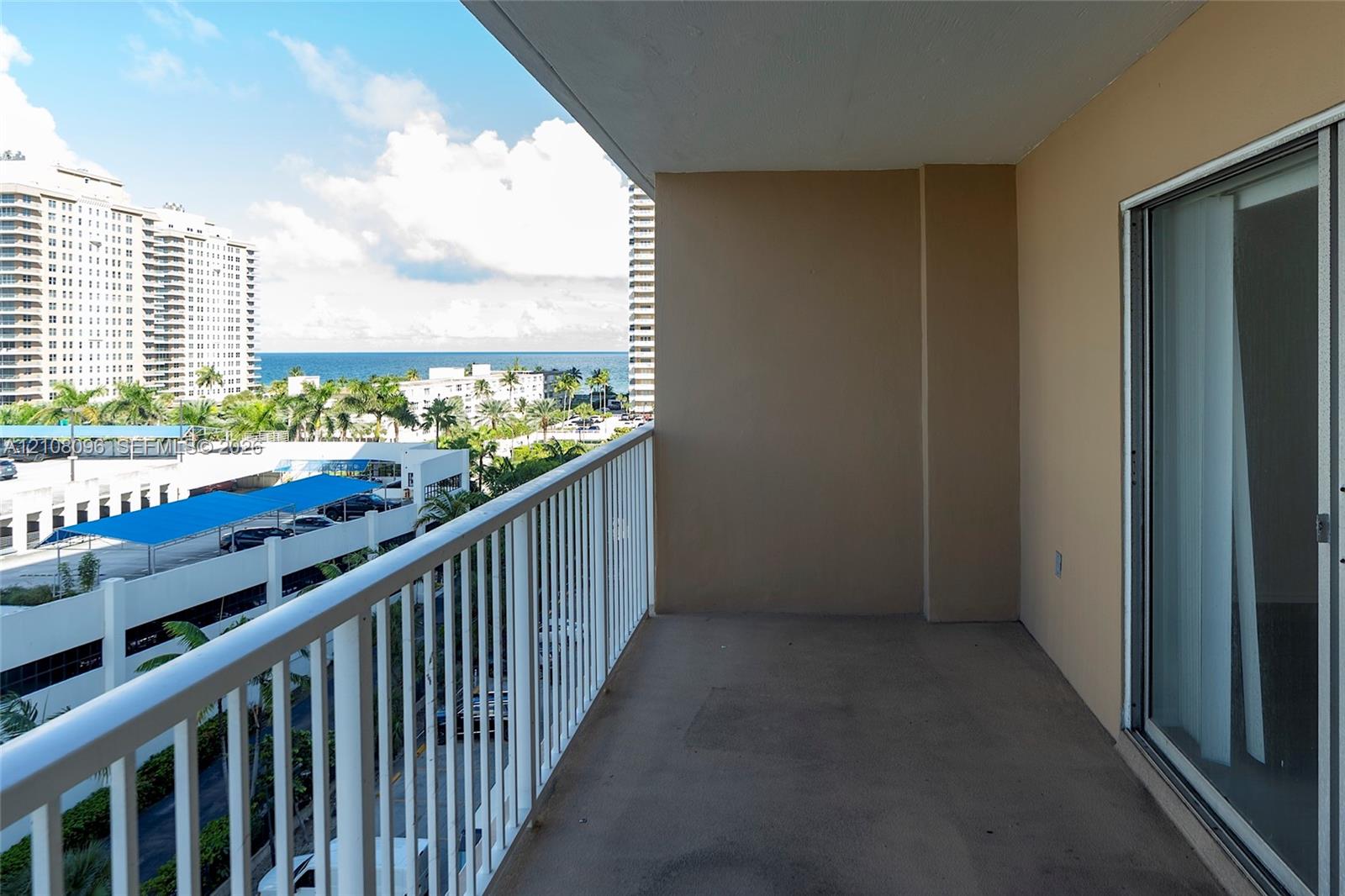 Covered balcony with white metal railings and sliding glass door entrance