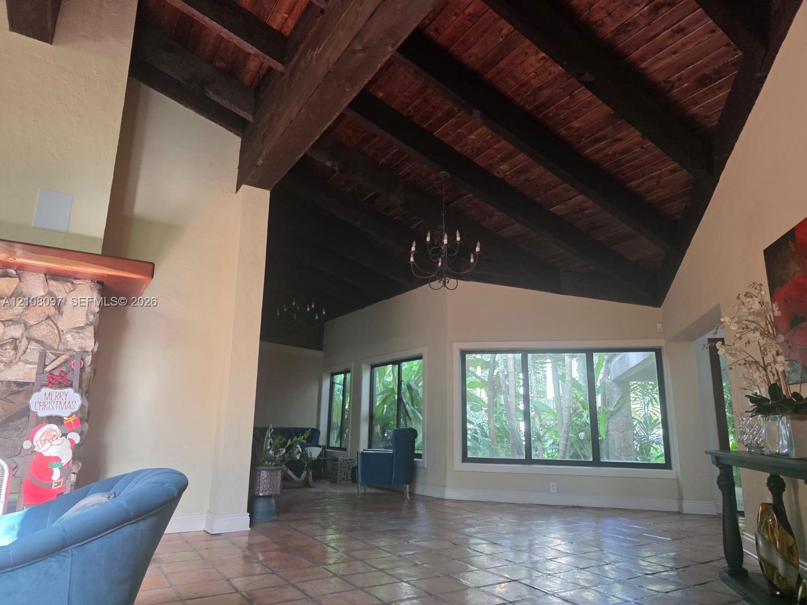 Vaulted ceilings with exposed timber beams and wood-plank detailing, masonry fireplace surround, and tile flooring
