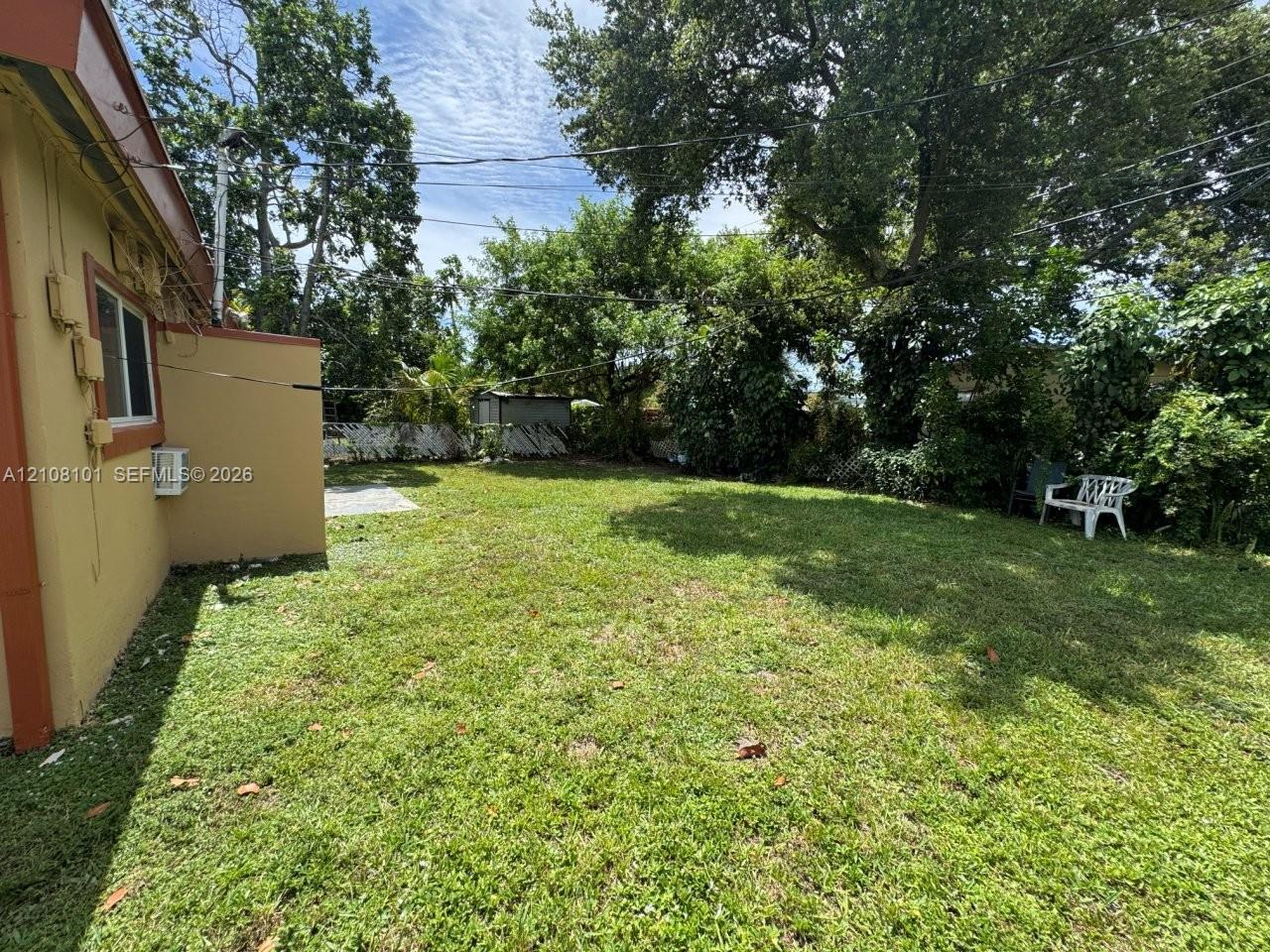 Expansive backyard featuring a lawn, perimeter fencing, and mature trees